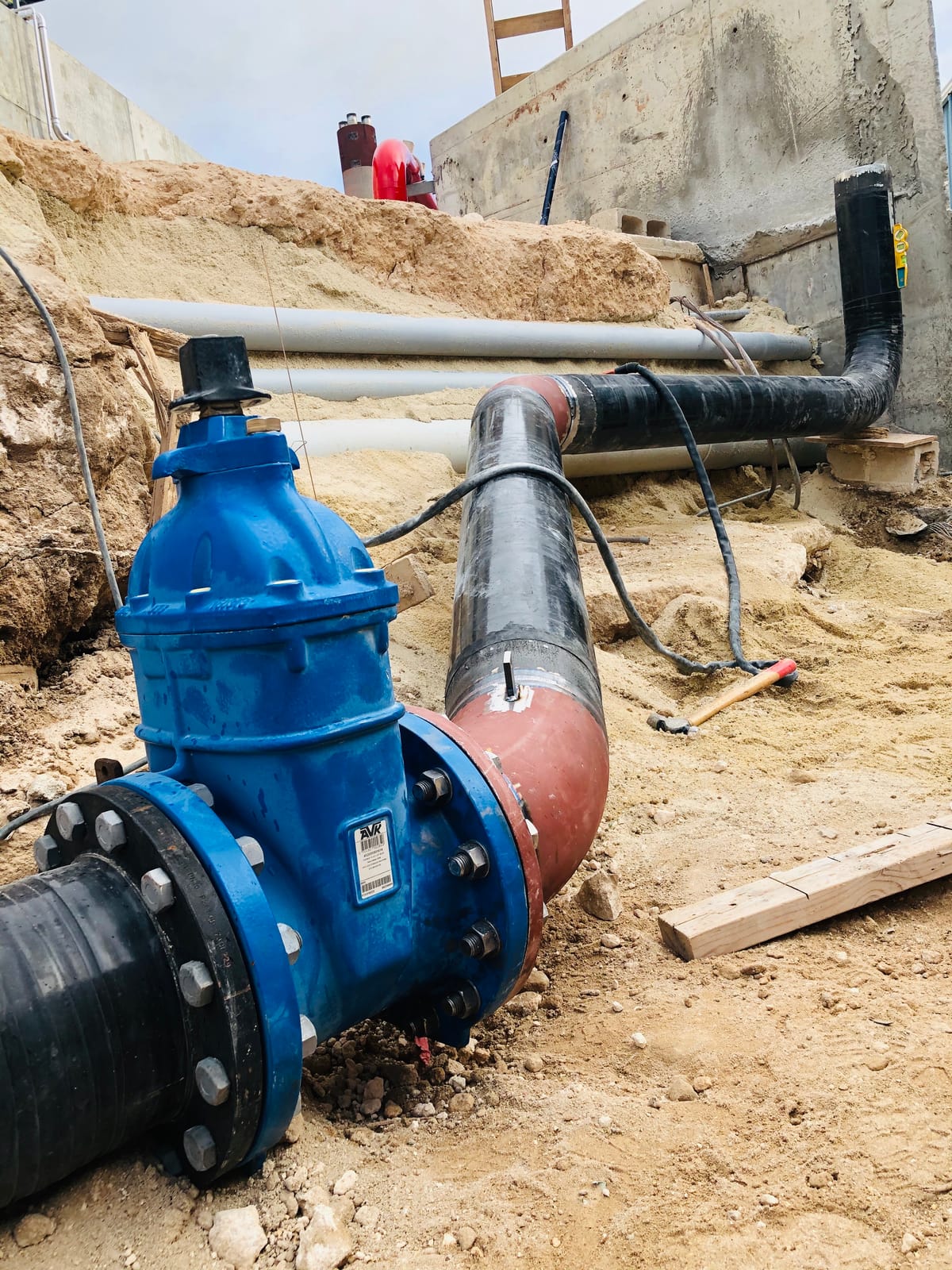Blue gate valve bolted between two coated sections of the fire main in the trench