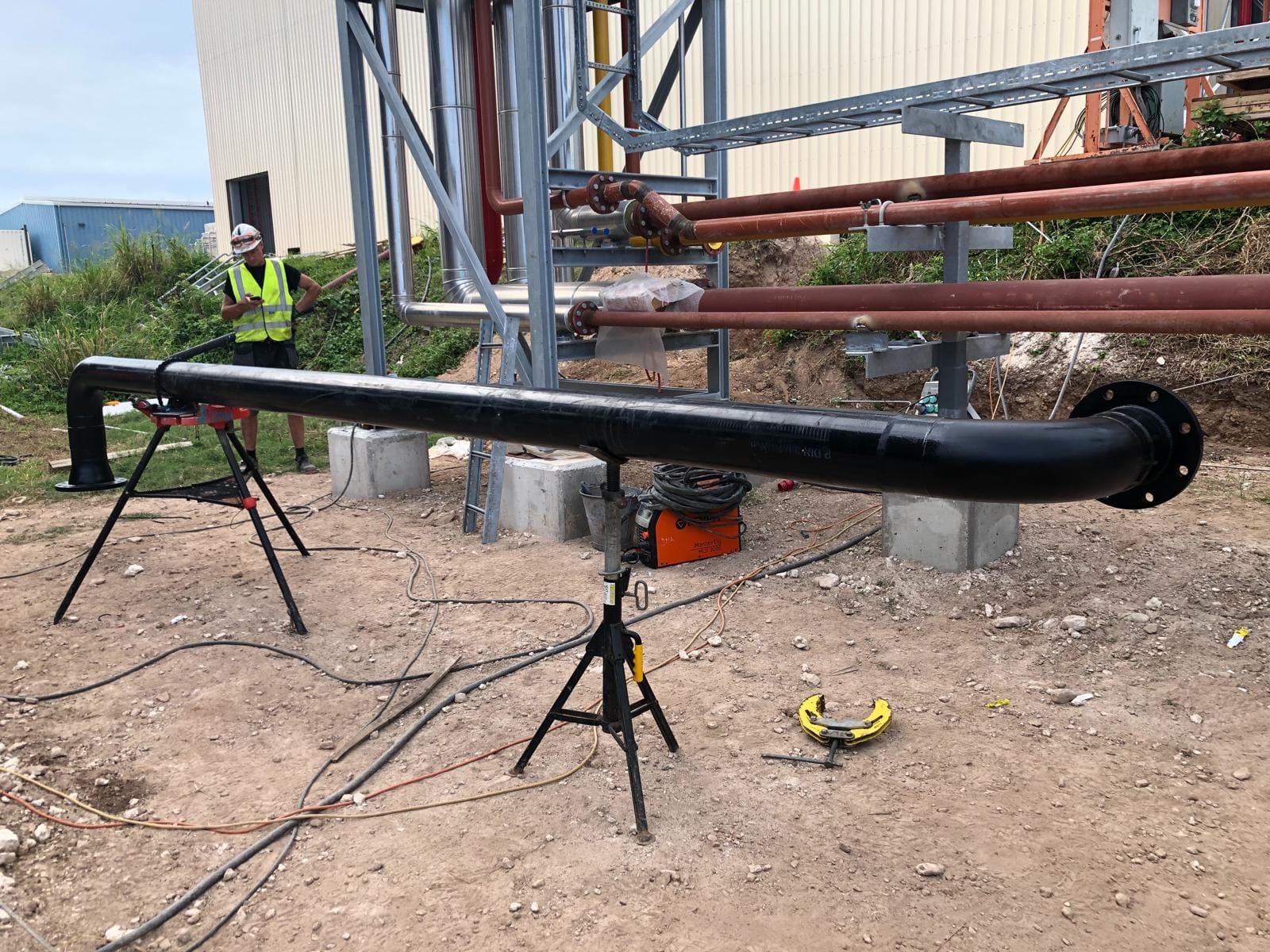 Prefabricated black-coated fire main spool set up on stands on site
